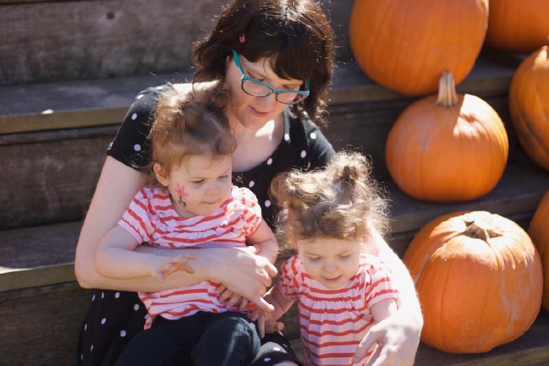 Wendy holding Everly and Chloe in amongst pumpkins.