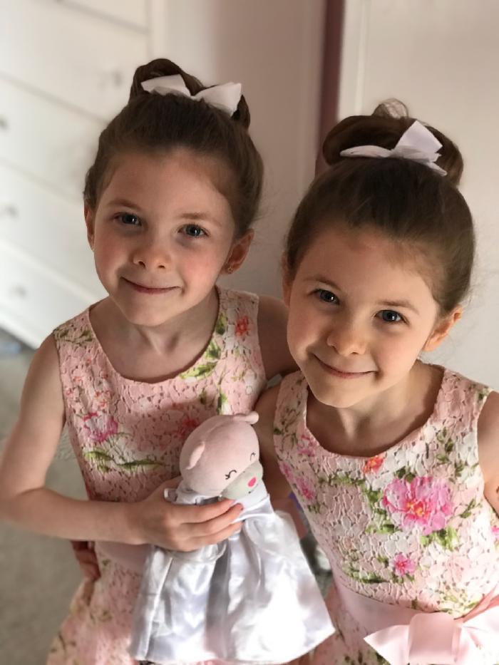 Identical twin girls in identical pink floral Easter dresses.