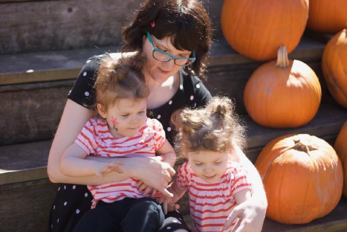 Wendy holding Everly and Chloe in amongst pumpkins.