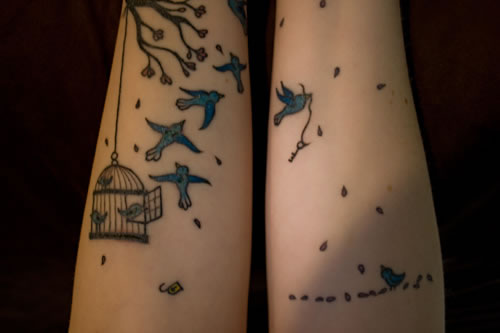 Tattoo of birds breaking free, a key, and a lock.