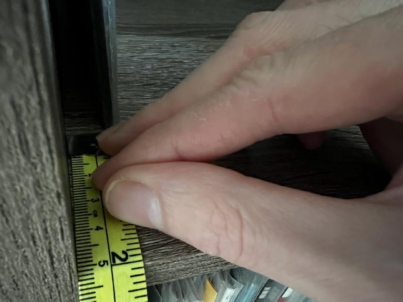 Measuring space from the record spine to the shelf’s front.