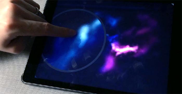 Finger touching an iPads screen as it paints blue clouds in space.