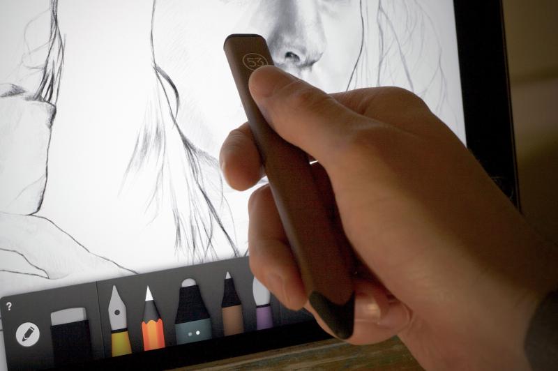 Hand holding a wooden Pencil stylus and using the eraser end to remove a mistake.