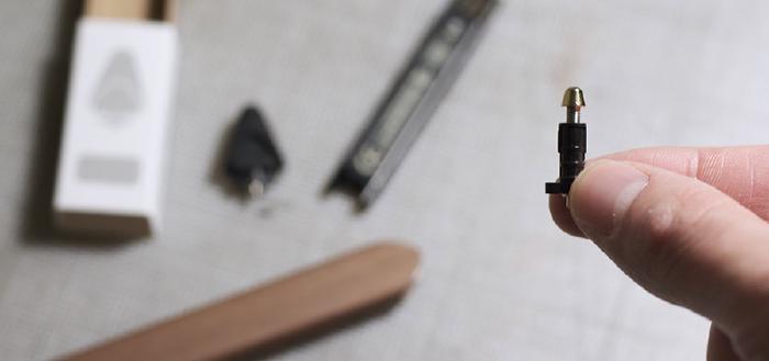 Hand holding a Pencil tip disassembled with spare parts blurred in the background.