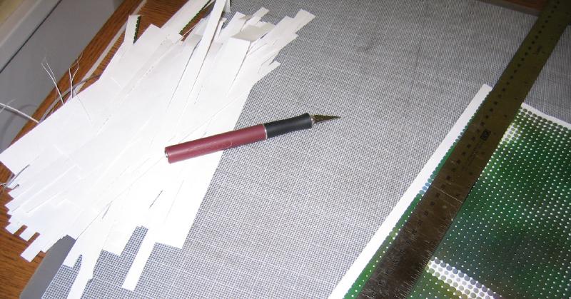 Trimmed white paper and a blade on top of a cutting mat